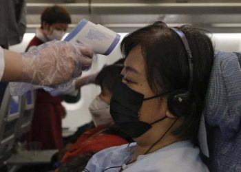 Flight attendants check temperatures of passengers aboard an Air China flight from Melbourne to Beijing on Feb. 4, 2020.         AP Photo/Andy Wong/The Conversation